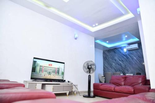 sala de estar con sofá rojo y TV de pantalla plana en Domi Smart 2 Bedroom Serviced Apartment with 24 hour Power, en Benin City