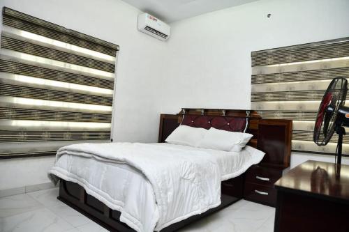 a bedroom with a large bed and two windows at Domi Smart 2 Bedroom Serviced Apartment with 24 hour Power in Benin City