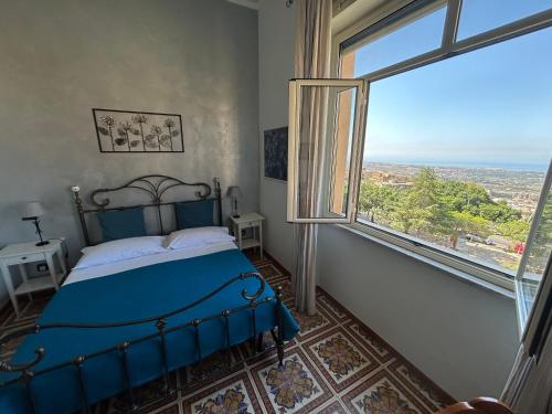 a bedroom with a blue bed and a large window at La Finestra sulla Valle in Agrigento