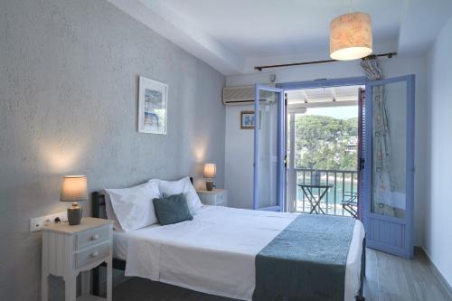 a bedroom with a white bed and a balcony at Levantes Hotel in Patitiri