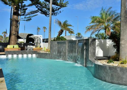 a swimming pool with blue water and palm trees at Peninsula All Suite Hotel by Dream Resorts in Cape Town