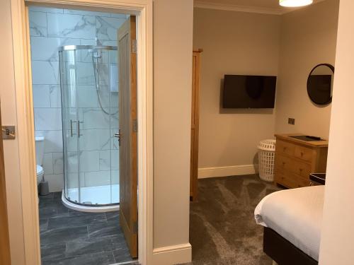 a bathroom with a shower and a television in a room at Jeffersons Abbey Road Serviced Apartments in Barrow in Furness