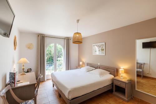 a bedroom with a bed and a desk and a window at Villa Sainte Anne in Porquerolles