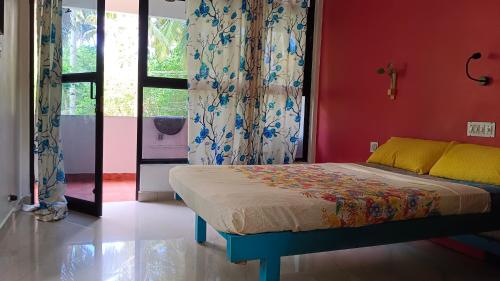 um quarto com uma cama e uma parede vermelha em Abhi's cafe avaduthura kovalam em Kovalam