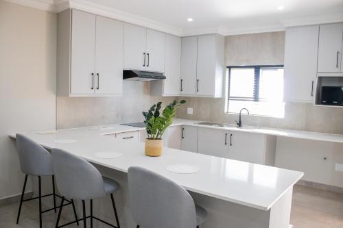 a kitchen with white cabinets and a white table and chairs at Asania Guest House in Bloemfontein