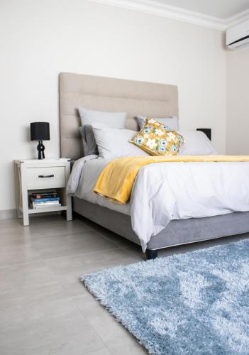 a bedroom with a bed and a blue rug at Asania Guest House in Bloemfontein