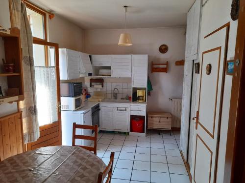 eine Küche mit weißen Schränken und einem Tisch im Zimmer in der Unterkunft Studio avec balcon amenage et wifi a Saint Gervais les Bains in Saint-Gervais-les-Bains
