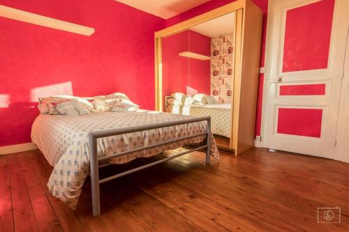 ein Schlafzimmer mit einer roten Wand mit einem Bett und einem Spiegel in der Unterkunft maison jardin terrasse in Le Tréport
