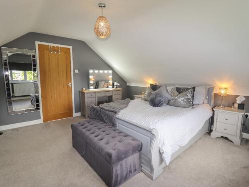 a bedroom with a large bed and a stool at 20 Glasfryn Avenue in Prestatyn