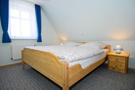 a bedroom with a wooden bed and a window at Ferienwohnungen Haus Hafenperle in Neuharlingersiel