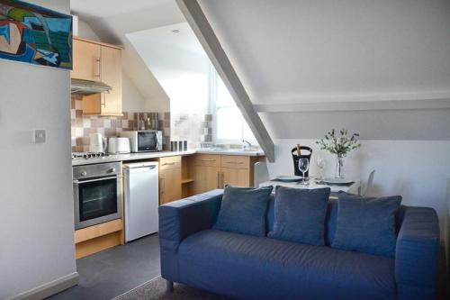 un soggiorno con divano blu in cucina di Modern Attic Studio Apartment with harbour views a Penzance