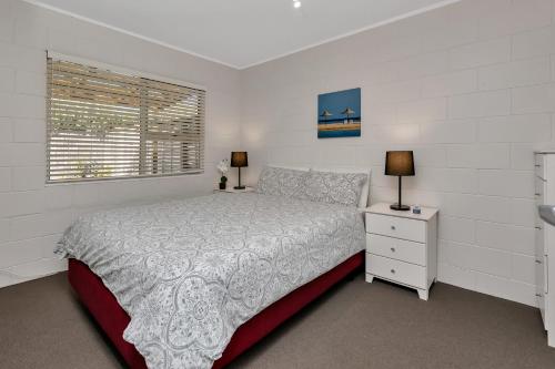a white bedroom with a bed and a window at Hidden Away - Tauranga Bay Holiday Unit in Mahinepua