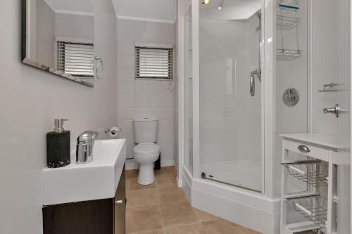 La salle de bains blanche est pourvue d'une douche et de toilettes. dans l'établissement Hidden Away - Tauranga Bay Holiday Unit, à Mahinepua