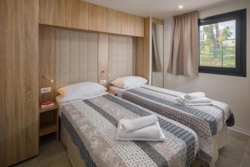 Dos camas en una habitación de hotel con toallas encima. en Premium Camping Homes Santa Marina, Lanterna, en Poreč