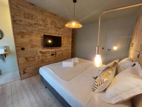 een slaapkamer met een groot wit bed en een houten muur bij MyDeer - Deluxe rooms & shared kitchen in Malmedy