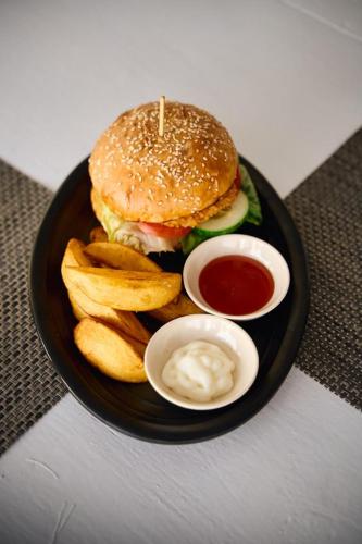 a plate with a hamburger and french fries and ketchup at Dream CoWork Hotel in Kuta Lombok