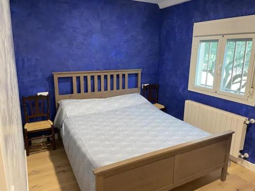 1 dormitorio con cama y pared azul en Casa Rural Piñuecar - Sierra Norte, en Piñuécar
