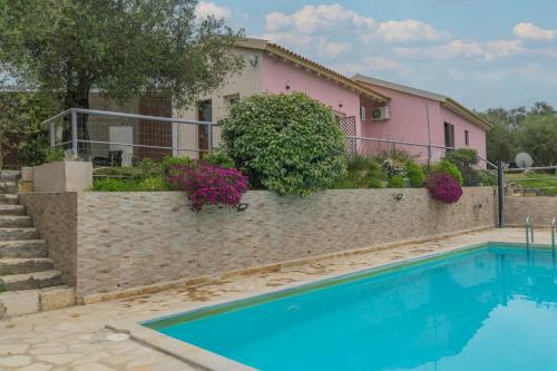 a house with a swimming pool in front of a pink house at Holiday Home Matthäus am Corfutrail, Ferienoase im Olivenhain 3 km zum Meer in Giannádes