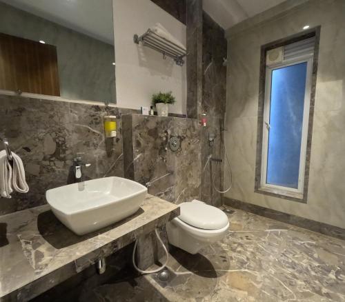 a bathroom with a sink and a toilet and a window at Maxxvalue Apartment Chandivali in Mumbai
