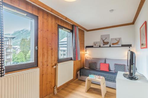 Cette petite chambre comprend un canapé et une fenêtre. dans l'établissement Résidence Pierre & Vacances La Rivière, à Chamonix-Mont-Blanc