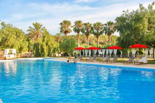 a swimming pool with chairs and red umbrellas at Llucatx Menorca in Son Parc