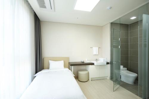 baño pequeño con cama y ducha en Pyeongchang The White Hotel, en Pyeongchang