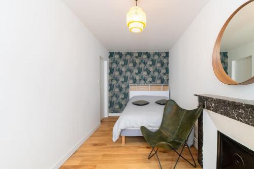 ein Schlafzimmer mit einem Bett, einem Spiegel und einem Stuhl in der Unterkunft Appartement Meuse & Mono, en hyper centre in Charleville-Mézières