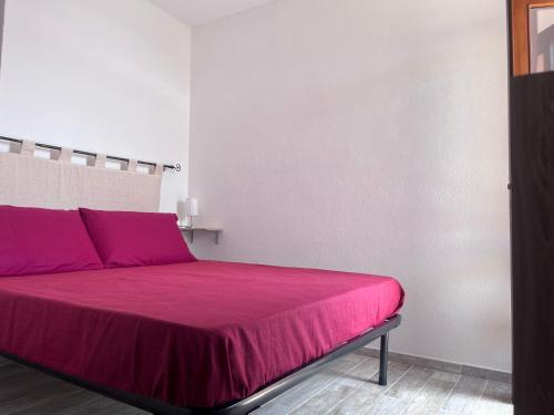 1 dormitorio con 1 cama con colcha rosa en L'angolo sul porto, en Palau
