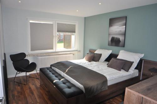 a bedroom with a bed with a chair and two windows at Ferienwohnung Deichland 65351 in Moormerland