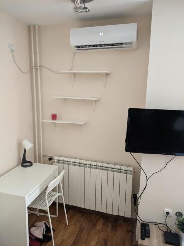 Zvezdara的住宿－NMD Apartments，客房设有书桌、电视和散热器。