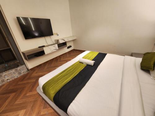 a bedroom with a large white bed with a flat screen tv at Express Square9 in Gurgaon