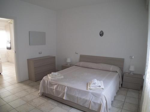 1 dormitorio blanco con 1 cama y 2 mesitas de noche en Condominio Belletti, en Lignano Sabbiadoro