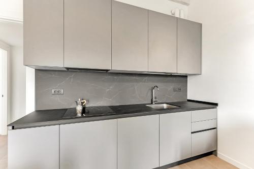 uma cozinha com armários brancos e um lavatório em Alessia's Flat- Naviglio Grande em Buccinasco