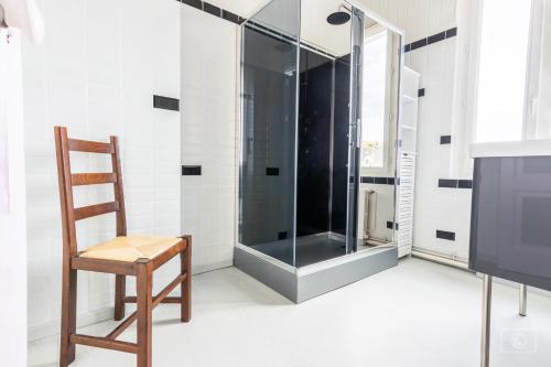 uma cabina de duche em vidro na casa de banho com uma cadeira de madeira em maison jardin terrasse em Le Tréport