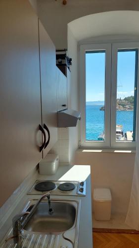 eine Küche mit einer Spüle und einem Herd sowie zwei Fenstern in der Unterkunft PORT in Makarska