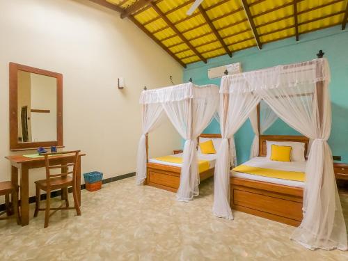 two beds in a room with a table and a mirror at Terrace Garden Ayurveda Resort in Weligama