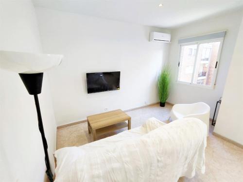 a living room with a white couch and a tv at Luminoso Apartamento enfrente del AVE in Puertollano
