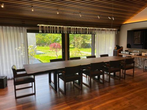 une salle à manger avec une grande table et des chaises en bois dans l'établissement 椿邸・TSUBAKI-Tei, à Jozankei