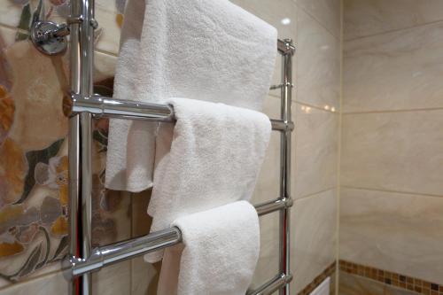 La salle de bains est pourvue de serviettes blanches sur un porte-serviettes. dans l'établissement Europa Hotel, à Irkoutsk