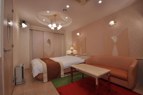 a hotel room with a bed and a couch at ホテル ネグレスコ in Tsukaguchi
