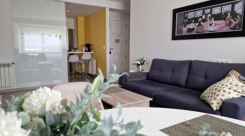 a living room with a blue couch and a table at Soleado a un Paseo de la Catedral in Santiago de Compostela