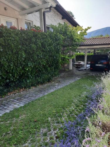 un jardín frente a una casa con un coche aparcado en Hiša odprtih vrat en Tolmin