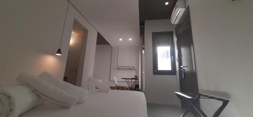 a white bedroom with a white bed and a window at Patio 101 in San Vito lo Capo