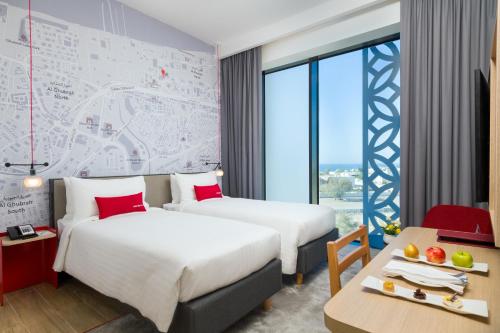 マスカットにあるIntercityHotel Muscatのベッド2台とテーブルが備わるホテルルームです。