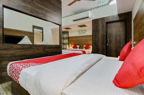 a bedroom with two beds with red pillows and a mirror at Collection O HOTEL TULIP PALACE in Jaipur