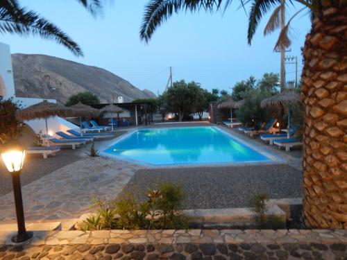a swimming pool in a resort with a palm tree at Petra Nera in Perissa