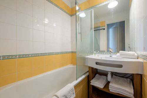 uma casa de banho com um lavatório, uma banheira e um espelho. em Résidence Pierre & Vacances Saskia Falaise em Avoriaz