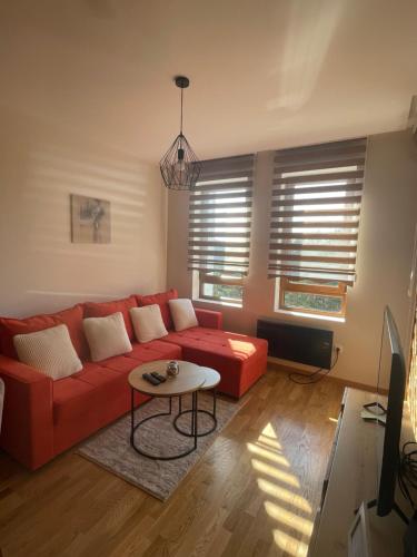 a living room with a red couch and a table at Apartman 21 Vila Elsa III Zlatibor in Zlatibor