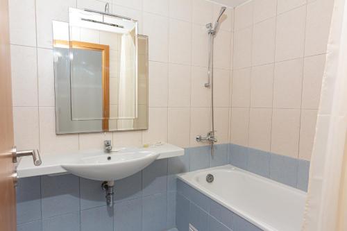 een badkamer met een wastafel, een spiegel en een bad bij Частен апартамент в затворен комплекс in Sinemorets