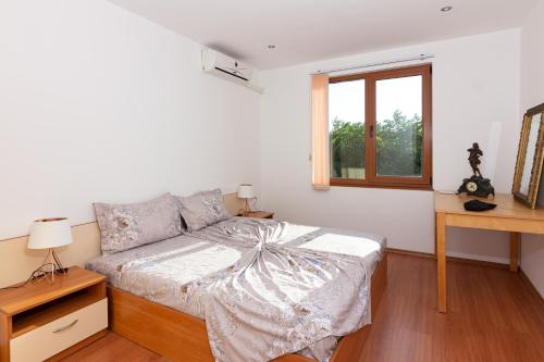 a white bedroom with a bed and a window at Частен апартамент в затворен комплекс in Sinemorets